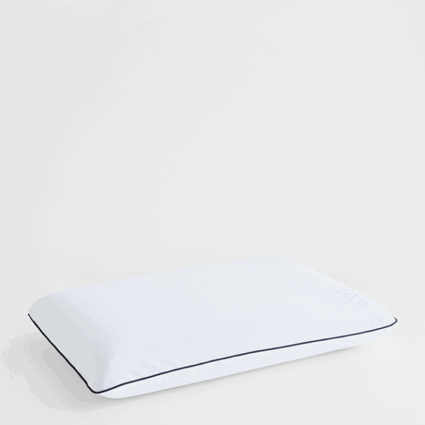 Angled side view of white cooling pillow protector on soft neutral surface