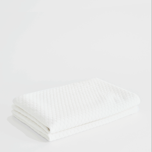 White cooling pillow protector stacked and folded on soft neutral background